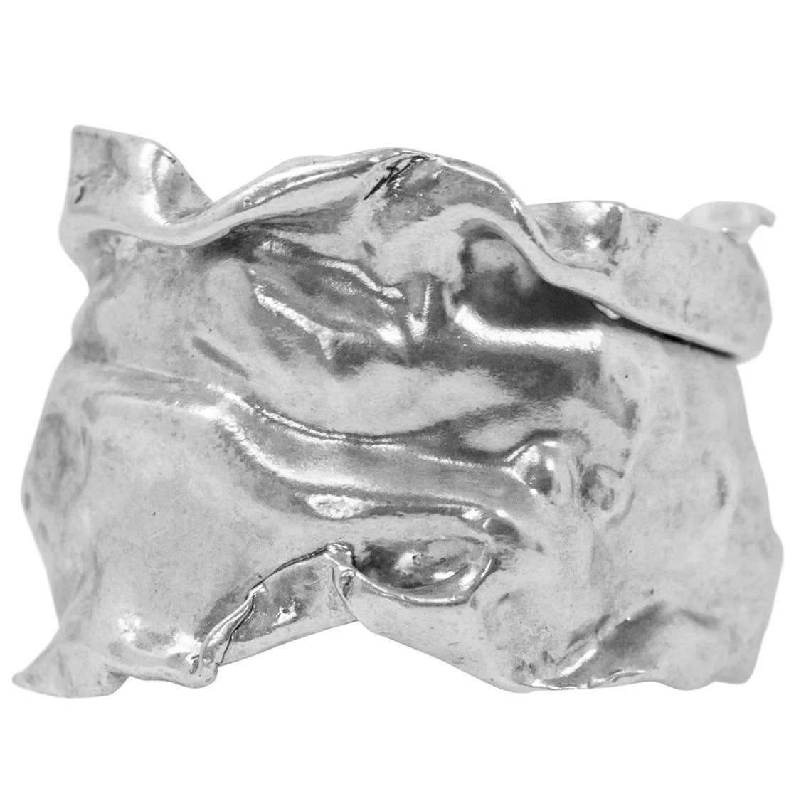 The Crumpled Foil Cuff Bracelet showcases a sculptural design with fluid, organic contours and sterling silver plating. Its irregular, wavy edges and textured, shiny surface resemble folded metal or flowing fabric. The abstract form of the bracelet creates depth and complexity, reflecting light off its polished curves and indentations.
