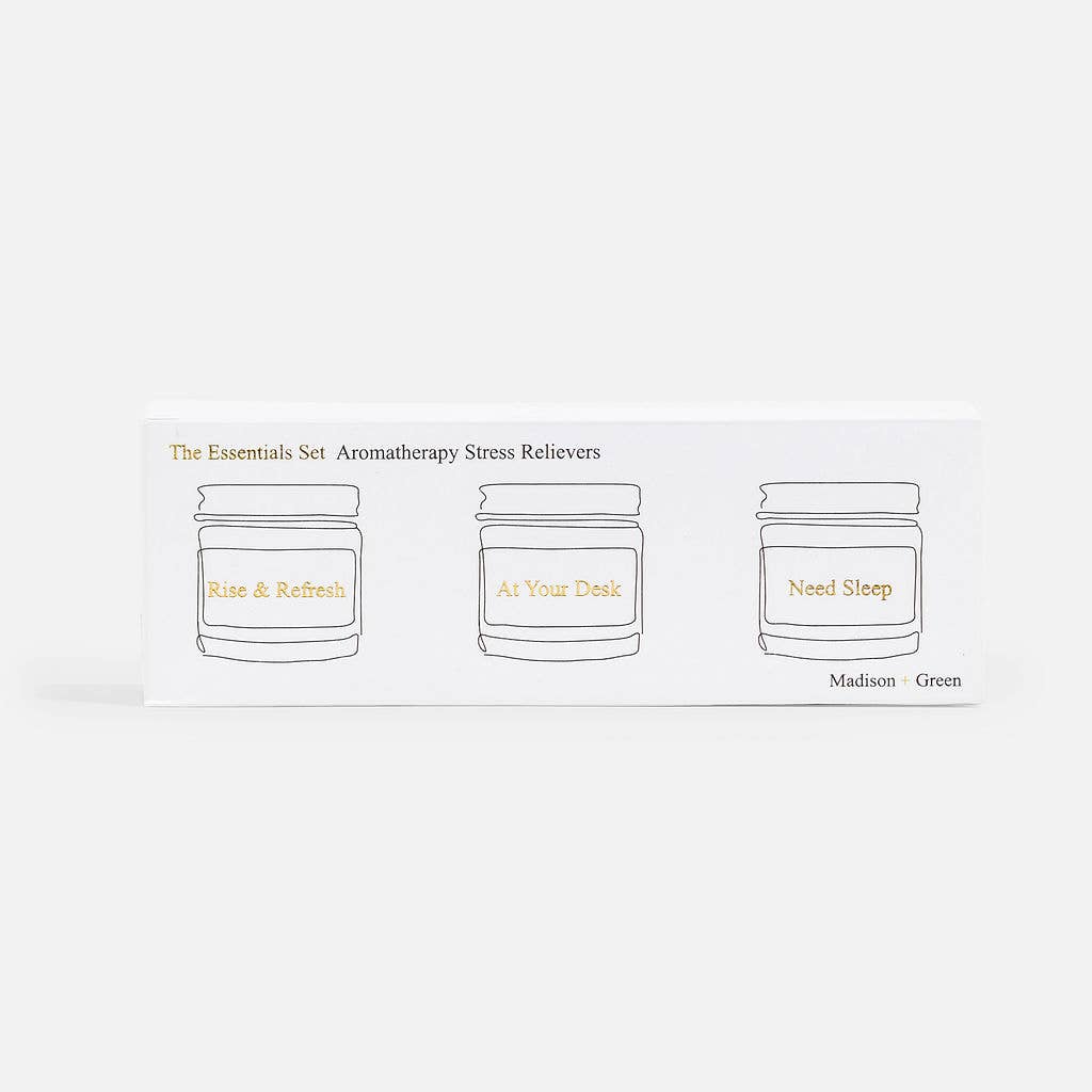 A white box labeled "The Essentials" Set of Three Aromatherapy Inhalers displays minimalist line drawings of three jars infused with essential oils. Each jar is marked: "Rise & Refresh," "At Your Desk," and "Need Sleep," featuring stress-relieving scents. In the bottom right corner, the text "Madison + Green" is printed.