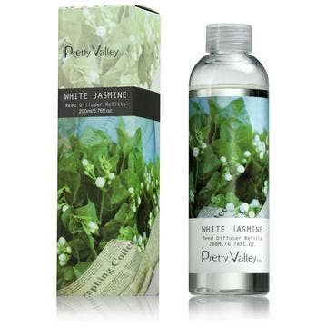 A bottle of Pretty Valley White Jasmine Diffuser Refill Oil stands next to its matching box, both decorated with blooming white jasmine flowers and green leaves. The clear bottle, which mirrors the box design, contains 200ml of liquid. Add a touch of Citrus Verbena for an invigorating twist to your fragrance experience.