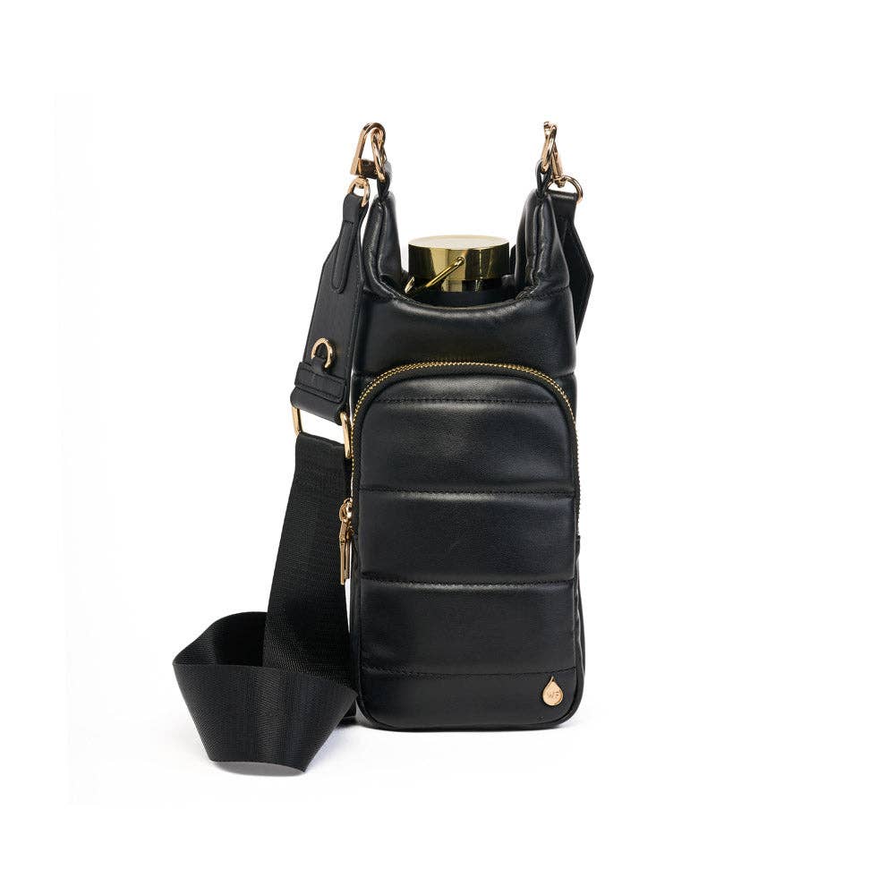 The Vegan Leather HydroBag® with Strap Bundle is a stylish and compact crossbody bag crafted from vegan leather, featuring a front pocket adorned with gold zippers and accents. It includes a wide, adjustable strap for hands-free convenience and a detachable section. The gold-colored HydroBag® water bottle fits perfectly into its designated compartment, providing a blend of functionality and chic style.
