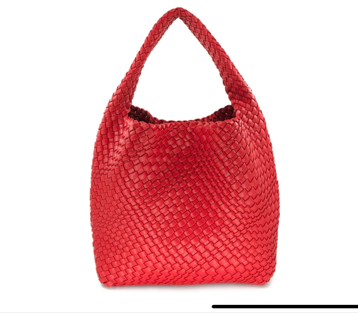The Woven Bag (Bag in a Bag) is fashioned from red woven PU leather and features a polished, curved design with a single handle. Its detailed basket-like pattern enhances both texture and style. Displayed against a plain white background, the bag's workmanship and sleek dimensions are prominently highlighted.