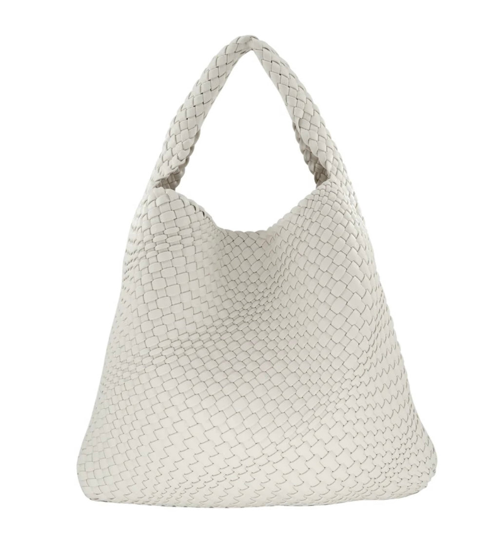 The Woven Bag (Bag in a bag) is displayed in white PU material, featuring a textured interlaced pattern. It boasts a single wide shoulder strap and offers a roomy, slouchy design that enhances its minimalist and elegant appeal. The woven construction contributes to the tactile character of the bag's overall look.