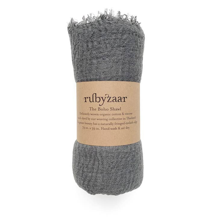A rolled gray Hima Large Scarf, Wrap, Shawl with a brown paper label wrapped around it. The label reads "rubyzaar" and describes it as "The Boho Shawl," crafted from organic cotton and rayon, hand-woven in Thailand. As a piece of sustainable fashion, its dimensions are 72 inches by 39 inches. Hand wash and air dry recommended.