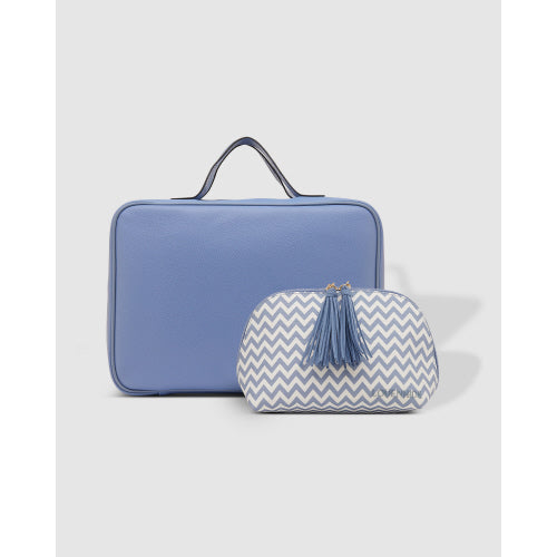 The Emma/Baby Audrey Cosmetic Bags - Set of 2 includes a light blue rectangular travel cosmetic case with a convenient handle positioned behind a smaller pouch. The front pouch is designed with an eye-catching white and blue chevron pattern adorned with blue tassels on the zipper. The plain light gray background beautifully highlights these stylish beauty cases.