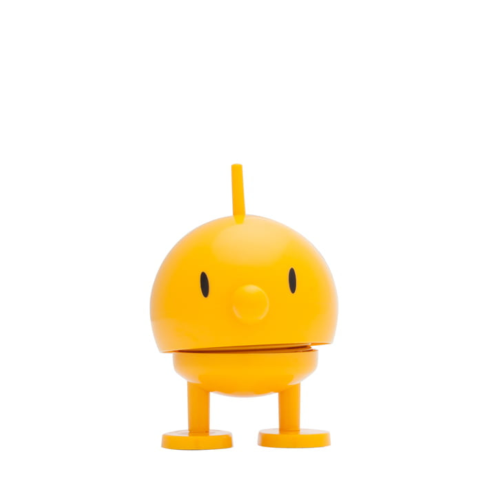 The Hoptimist Bumble is a small, yellow, spherical toy featuring a minimalist design with a simple face and short antenna on top. It has black eyes, a tiny nose, and two sturdy legs with flat, round feet. Standing upright against a plain white background, it embodies the charm of Danish design history and adds cheerful vibes to any home decor.