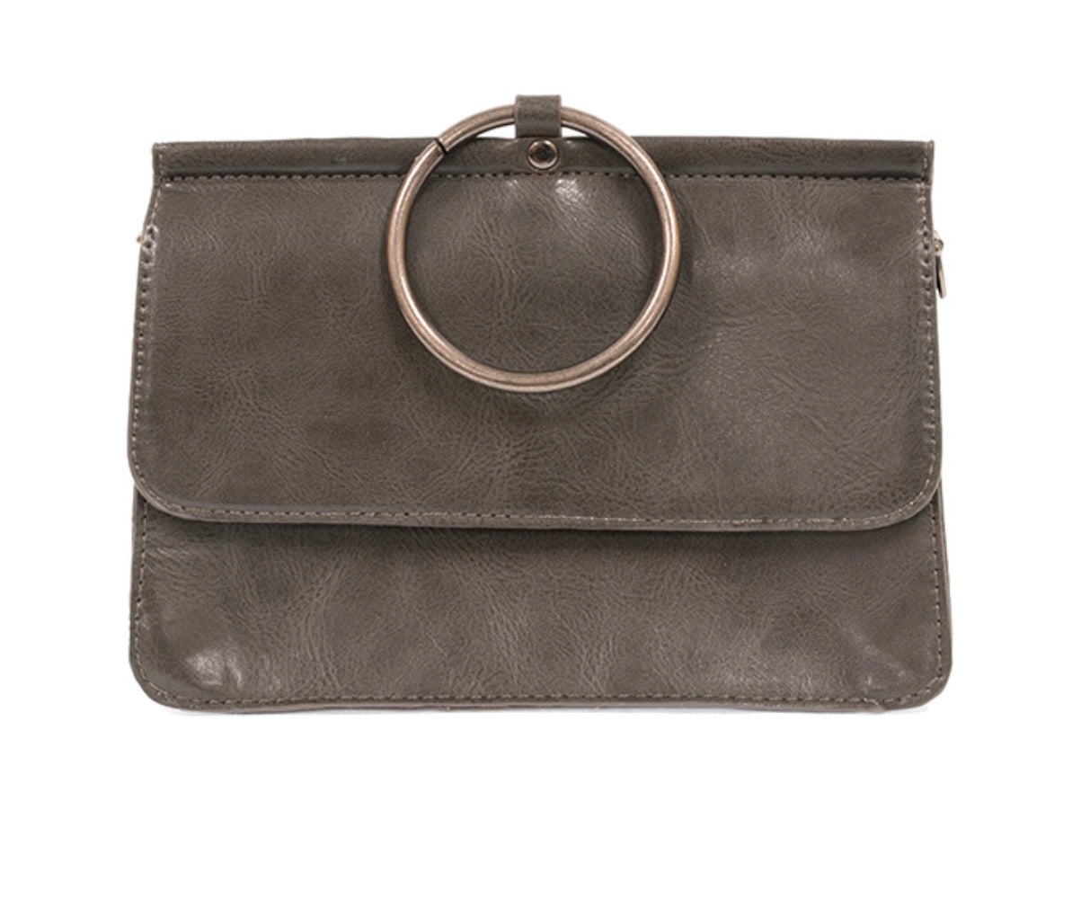 The Aria Ring Bag - Fall/Winter is a brown vegan leather clutch featuring a large silver metal ring on top. It boasts a smooth texture with a fold-over flap, embodying minimalist design with clean lines. The elegance of this bracelet bag shines through without any visible branding or embellishments.