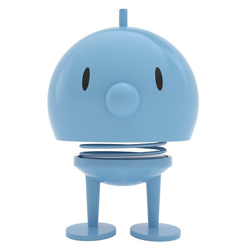 The Hoptimist Bumble embodies the charm of Danish design history with its blue, round, cartoonish figure featuring a large head, small black oval eyes, and a small cylindrical nose. Its spring neck and simple legs make it not only playful but also a delightful piece of home decor inspired by the classic Hoptimist.