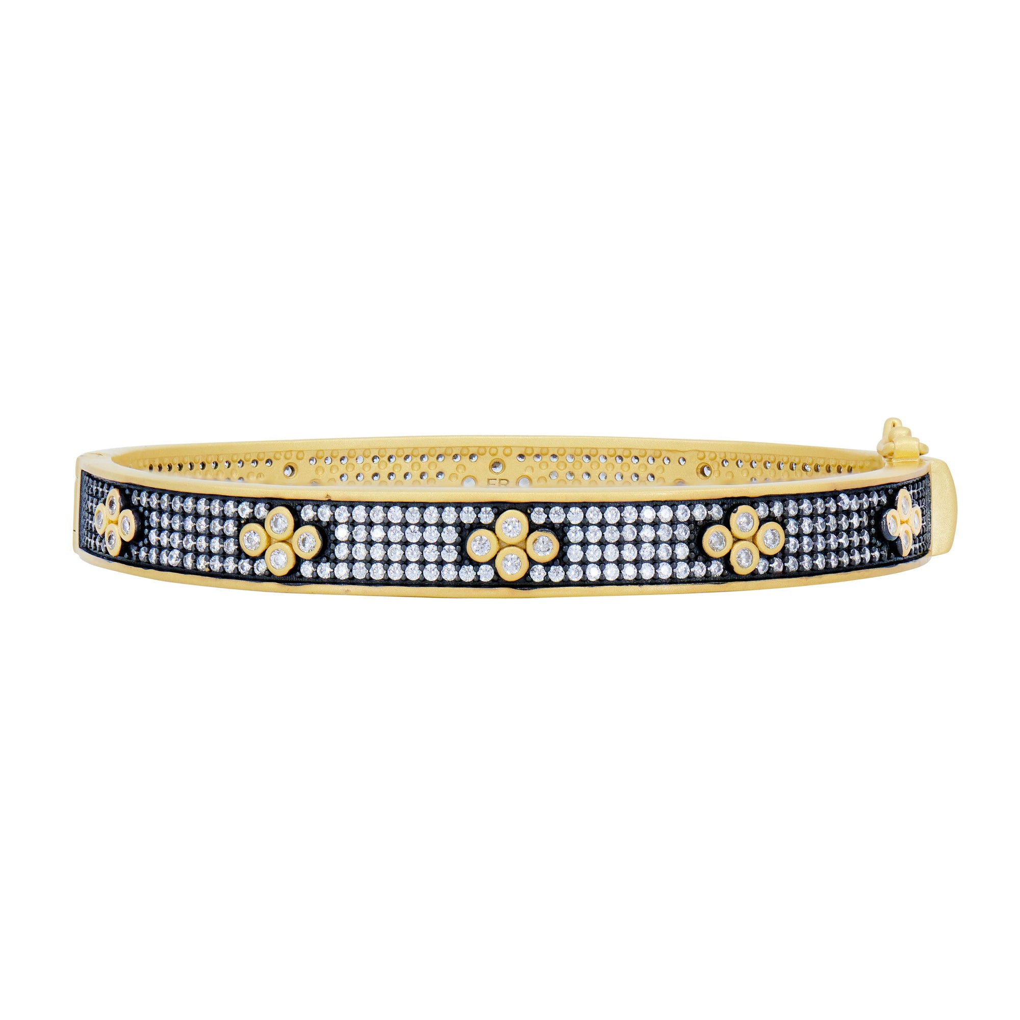 The Signature Brooklyn in Bloom Clover Hinge Pave Bangle showcases a gold bangle with a black rhodium background and intricate floral designs. Its surface is adorned with flowers made from clusters of sparkling white stones. This accessory features a sleek, polished finish for an elegant and luxurious touch.