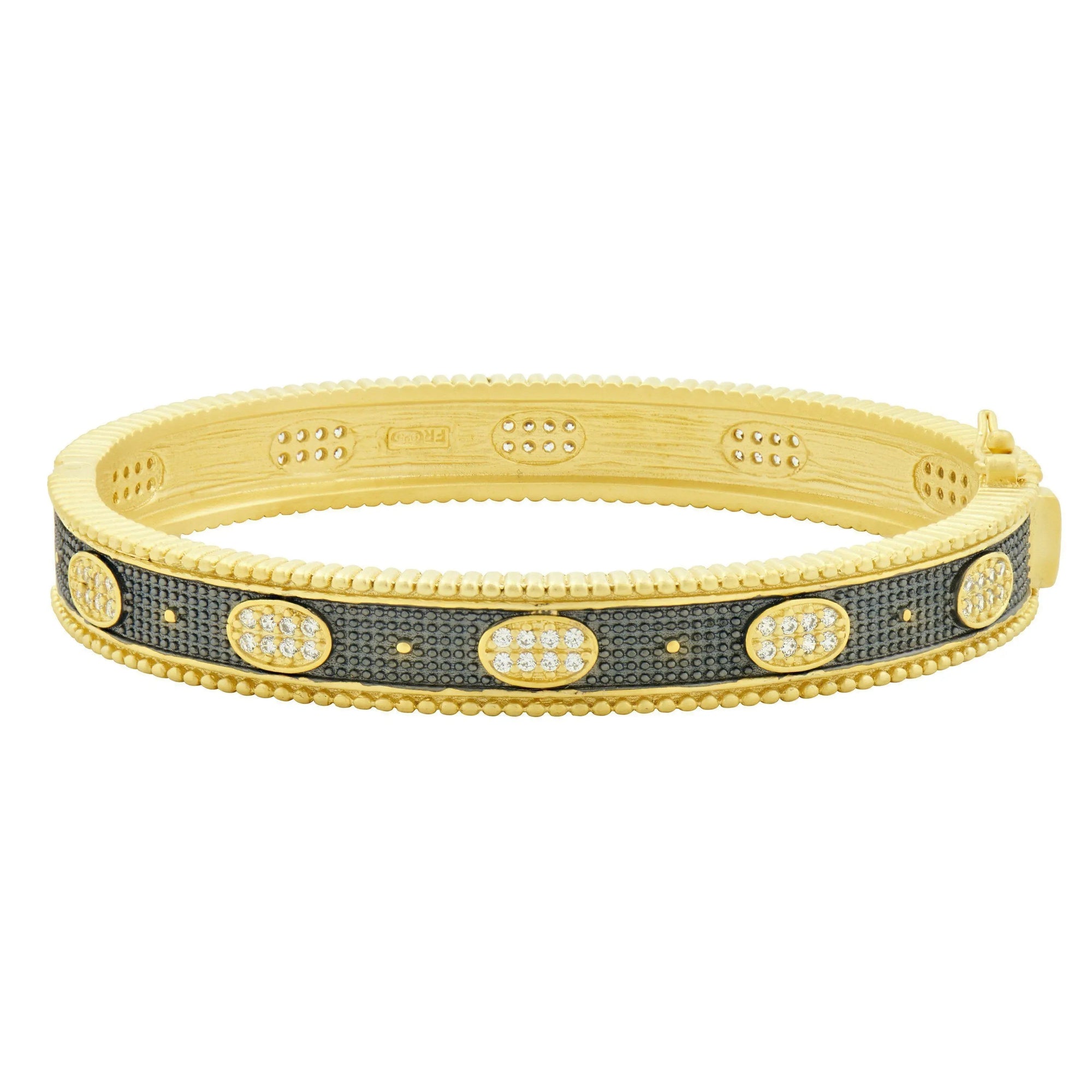 The Stack This! Oval Eternity Hinged Bangle features a textured band with a 14K gold finish, highlighted by oval sections embedded with small, shimmering diamonds. Its beaded edge and clasp closure provide a mix of matte and glossy tones, offering an elegant and sophisticated flair.