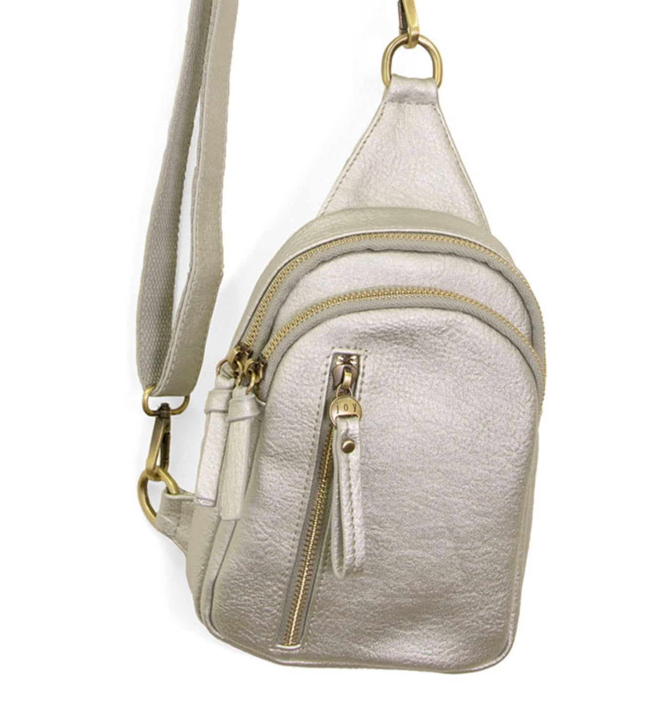 The Skyler Sling Bag is a compact metallic silver crossbody made from vegan leather with an adjustable, convertible strap. It features a main zippered compartment, a front zippered pocket, gold-tone hardware including rings and zipper pulls, and a textured surface.