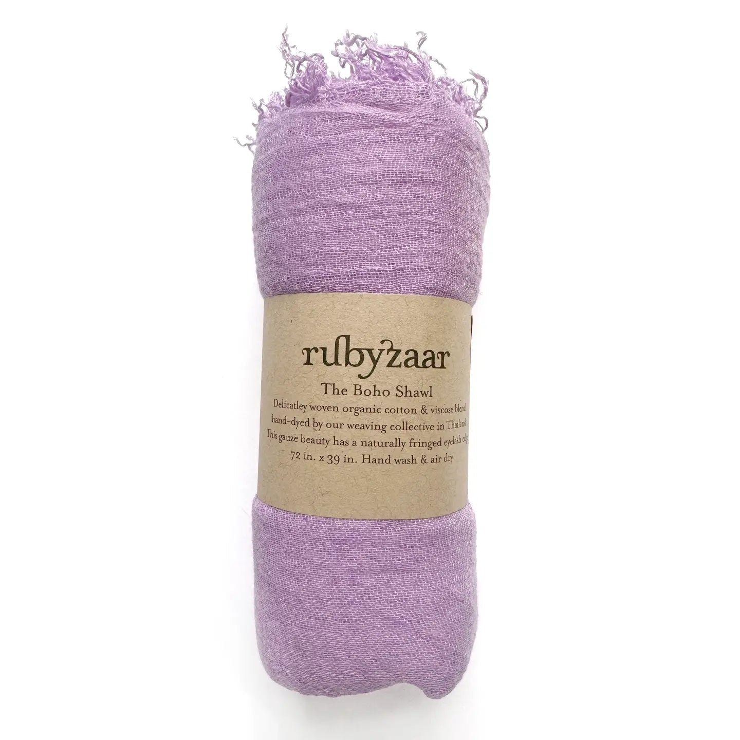 A rolled-up lavender bohemian-style scarf with fringed edges is wrapped in a brown paper label. The label displays "rubyzaar" and "The Boho Scarf," emphasizing that it's hand-dyed and woven from organic cotton and viscose. It measures 72 x 39 inches and comes with care instructions advising hand washing and air drying.