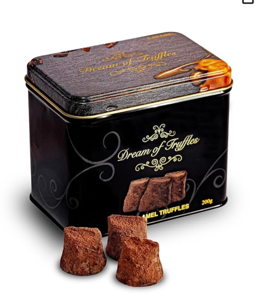 A sleek, rectangular metal tin labeled "Dream of Truffles" with gold swirls and sea salt truffle images holds 200g of gourmet indulgence. The luxurious black tin featuring Cocoa Dusted Truffles exudes gift-worthy allure beside irresistibly beckoning caramel truffles.