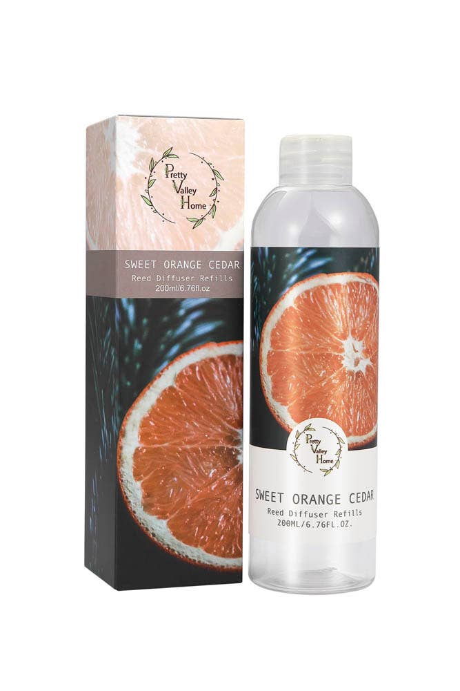A clear plastic bottle of "Sweet Orange Cedar" Diffuser Refill Oil, crafted by "Pretty Valley Home," features notes of Citrus Verbena and an orange slice image. It comes with a matching box and contains 200ml (6.76 fl oz) of refreshing liquid.