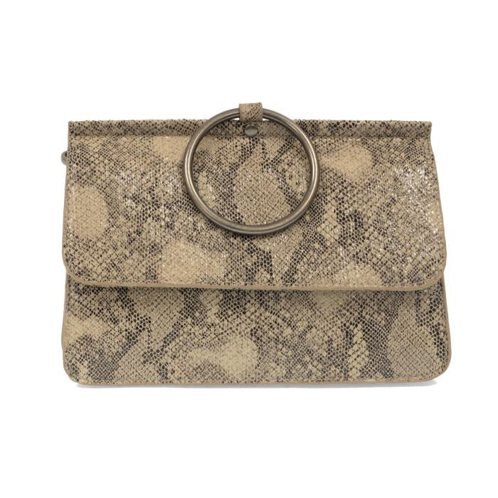 The Aria Ring Bag - Fall/Winter features a sleek snakeskin-patterned design in beige and brown vegan leather, highlighted by a prominent round metal ring handle affixed to its flap. Its textured surface showcases a variety of shades and scales, adding depth to the bag's elegant form. With its sophisticated yet adaptable style, it suits both formal and casual occasions perfectly.