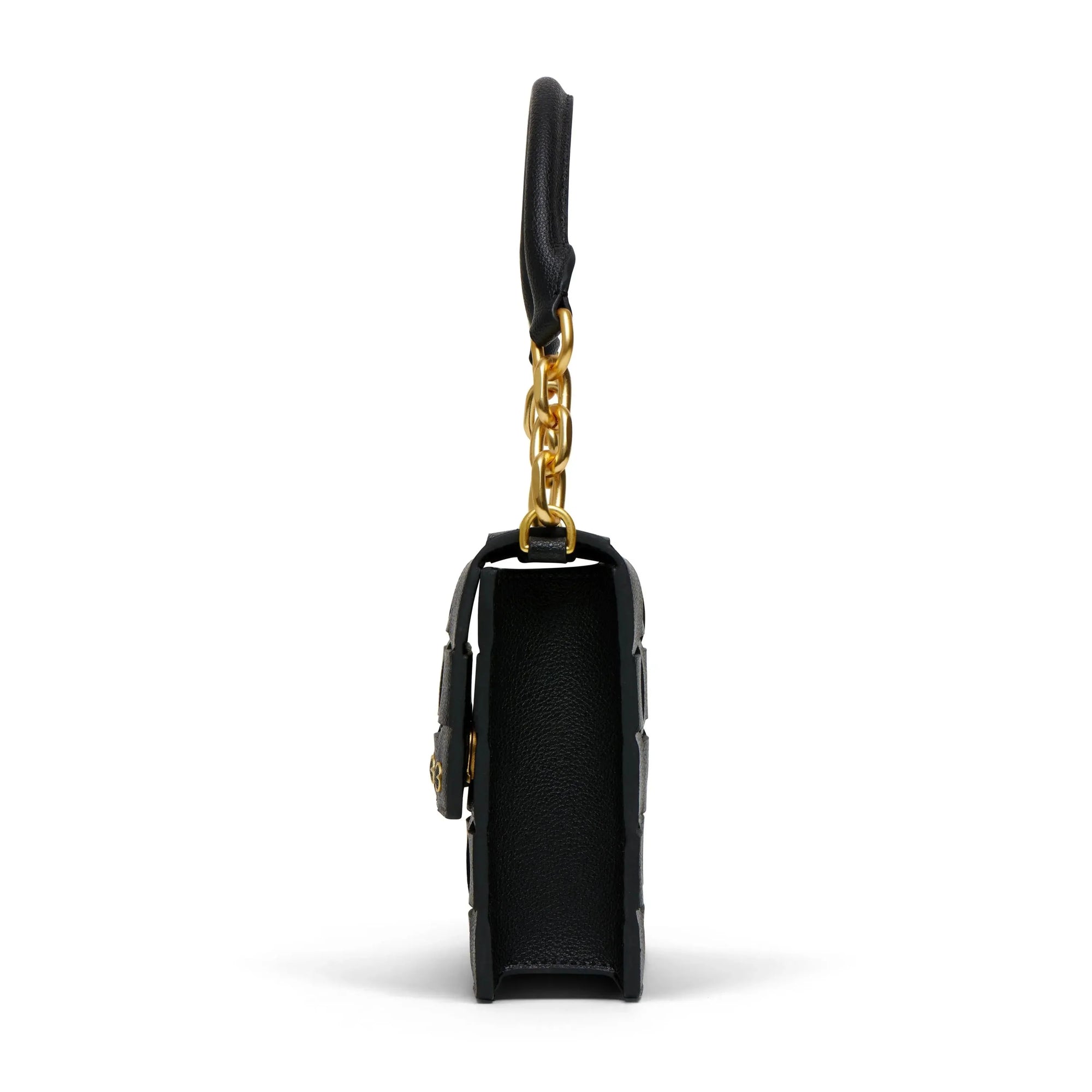 This side view showcases The Bedford Handbag, a Brooklyn-inspired accessory made from luxurious Italian Nappa leather in black. It features elegant gold chain detailing, a smooth texture, and a chain handle gracefully attached to the top. Its slightly curved rectangular shape is highlighted against a pristine white background.