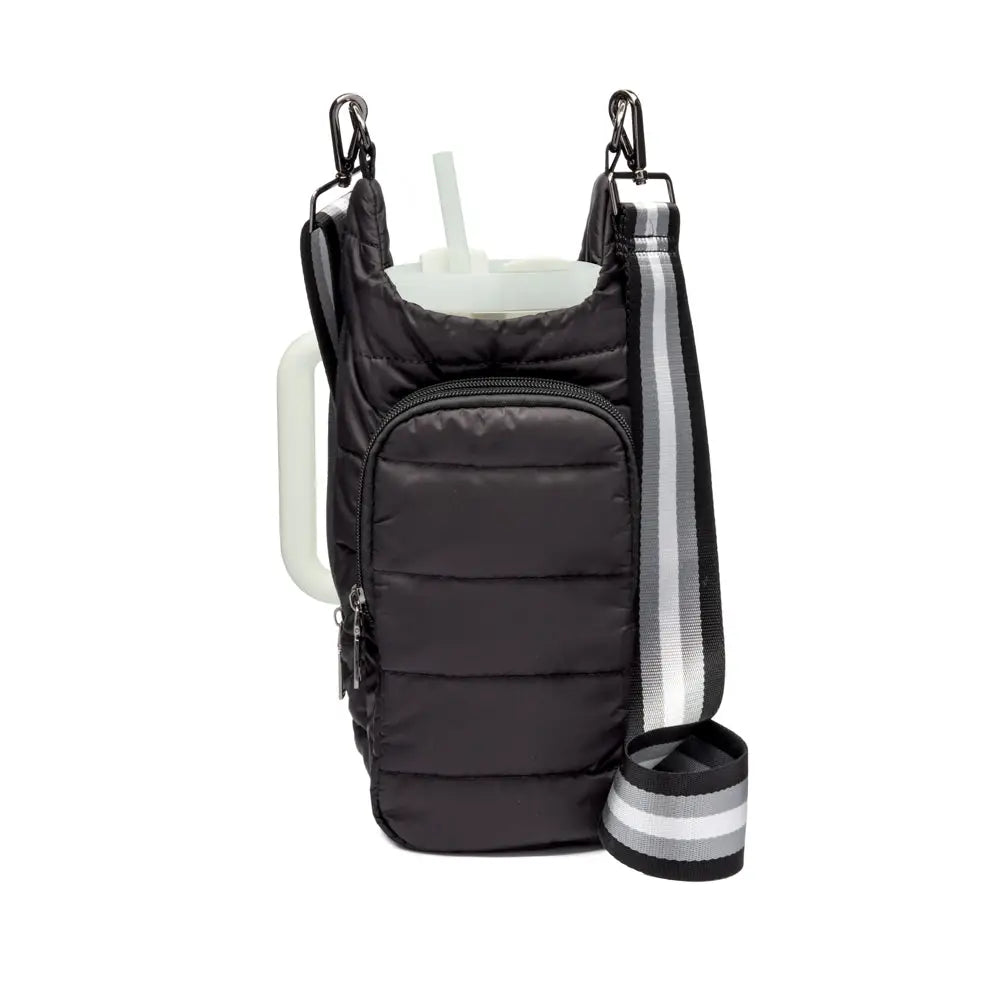 The HydroBag Handle is a black quilted water bottle sling featuring a front zippered pocket and carabiner attachments. It includes an adjustable black strap with white and gray stripes. The sling partially reveals a clear water bottle secured by an elastic straw holder for spill-free hydration.