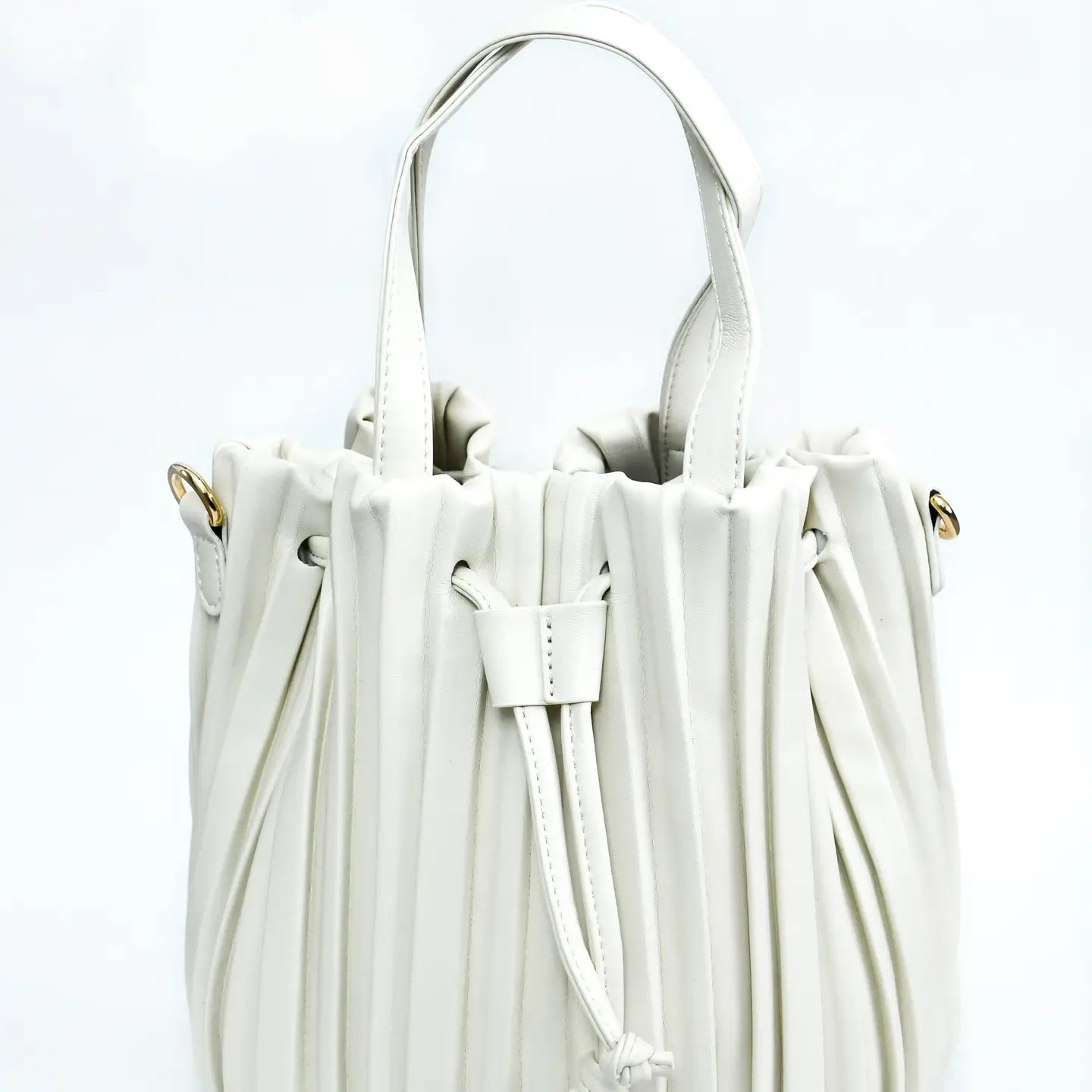 The Pleated Bucket Bag is a chic white handbag with a drawstring closure, ideal for any occasion. It features short handles and gold-tone hardware accents on the sides, offering an elegant and minimalist design that makes it a sophisticated modern accessory.