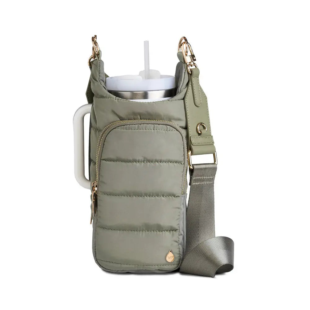 The HydroBag Handle, a padded green crossbody bag with a front zippered pocket and gold zipper, is designed to hold a large white tumbler. It features an elastic straw holder and an adjustable strap with gold hardware, highlighting its practical design for carrying drinks.