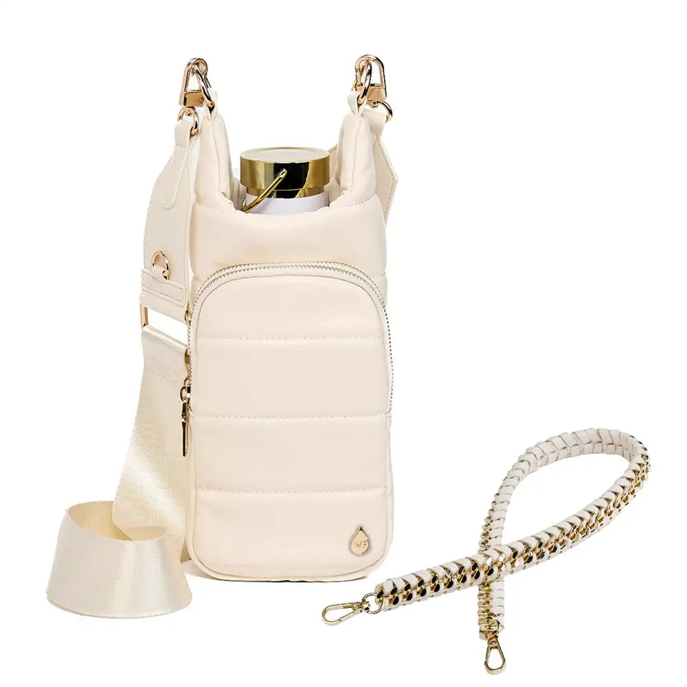 The Vegan Leather HydroBag® with Strap Bundle is a beige quilted holder made from vegan leather, featuring a detachable strap for hands-free wear, front zip pocket, gold accents, an extra gold chain strap, and includes a metal water bottle with a gold cap.