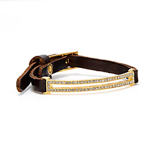 The Skinny Pave Rectangle Leather Bracelet in Gold features luxurious Italian brown leather, an 18K gold-finished rectangular clasp adorned with two parallel rows of sparkling rhinestones, beautifully displayed on a white background with one end slightly curled.