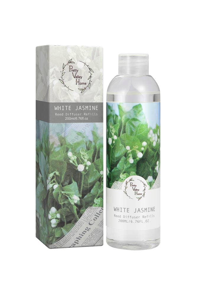 The image displays a bottle and box of Diffuser Refill Oil from Pretty Valley Home, featuring a white jasmine fragrance. The clear plastic bottle holds a floral-scented liquid and is decorated with a label that has green leafy designs. The box mirrors this floral theme and includes product details along with volume information.