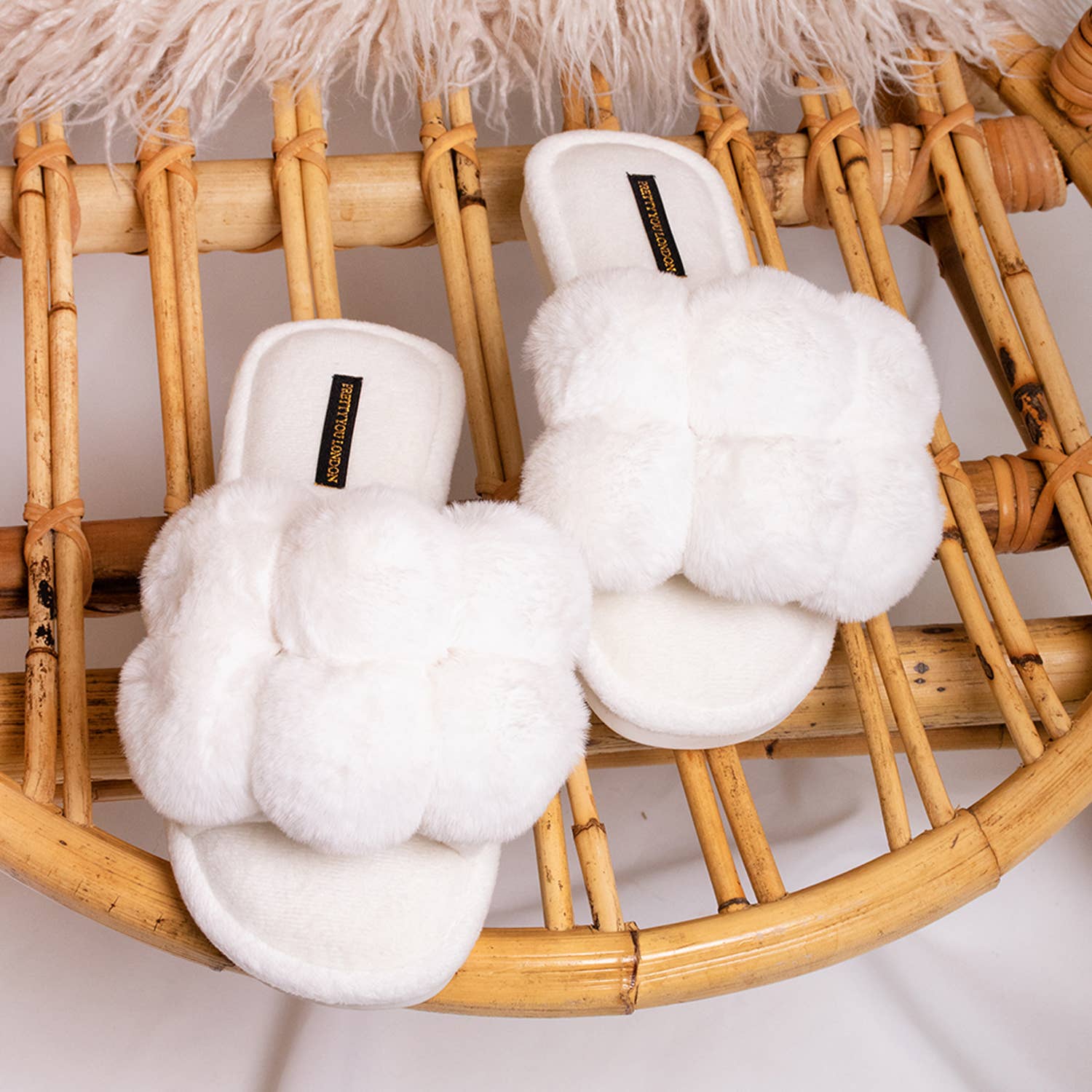white pom pom slippers on a bench