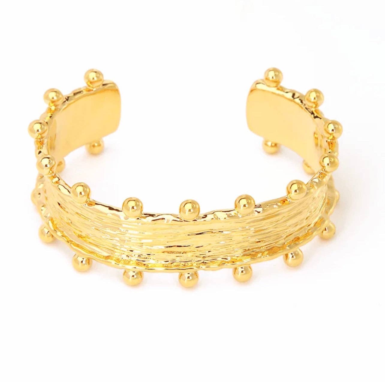 The Raina Studded Cuff is a textured hypoallergenic gold cuff bracelet with a wide band showcasing a woven design. It features small gold spheres evenly spaced along the top and bottom edges, adding detail and dimension. This 18K Gold Plated piece has an open-ended design for easy wear and boasts a shiny, polished finish.