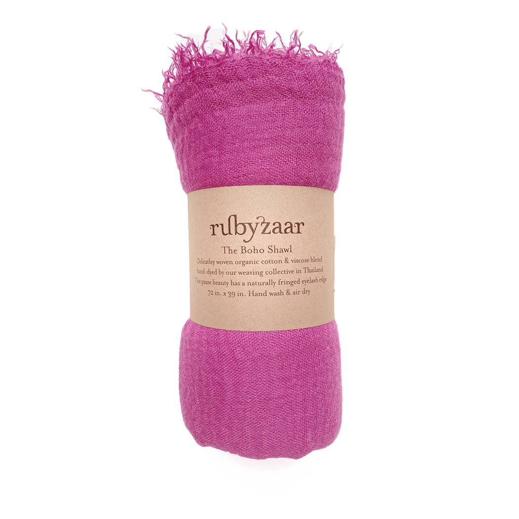 A rolled-up, magenta boho scarf with fringed edges is wrapped in a label that reads "rubyzaar The Boho Shawl." This bohemian style accessory is a hand-dyed blend of organic cotton and viscose, crafted in Thailand. Measuring 72x39 inches, it recommends hand washing and air drying for care.