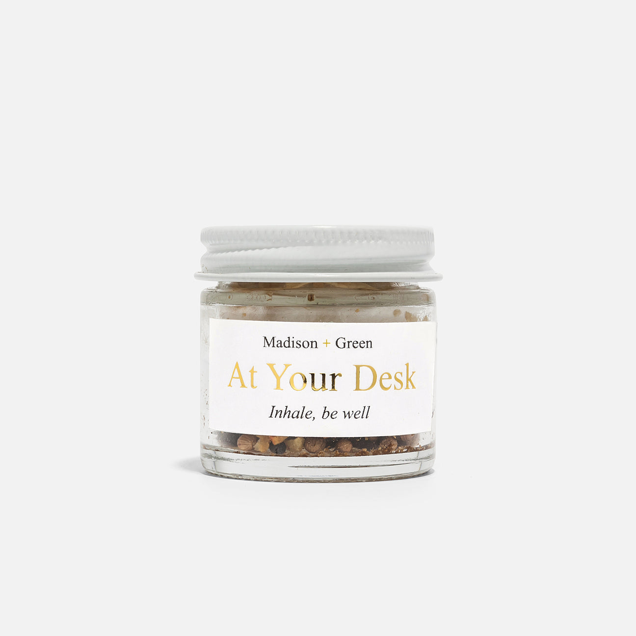 In a small glass jar with a white lid, the botanical potpourri mix infused with essential oils for stress relief is beautifully displayed. The label features "Aromatherapy Inhalers - 13 varieties" from Madison + Green inscribed in elegant gold and black text against a plain, soft gray background that accentuates the product.