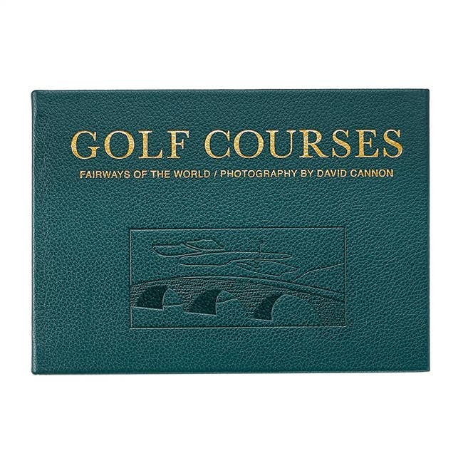The "Golf Courses - Fairways of the World" leather-bound edition features David Cannon's stunning photography of golf courses, accented with gold lettering on the cover. It includes an embossed design depicting a famous golf course landscape complete with a bridge, capturing iconic scenes.