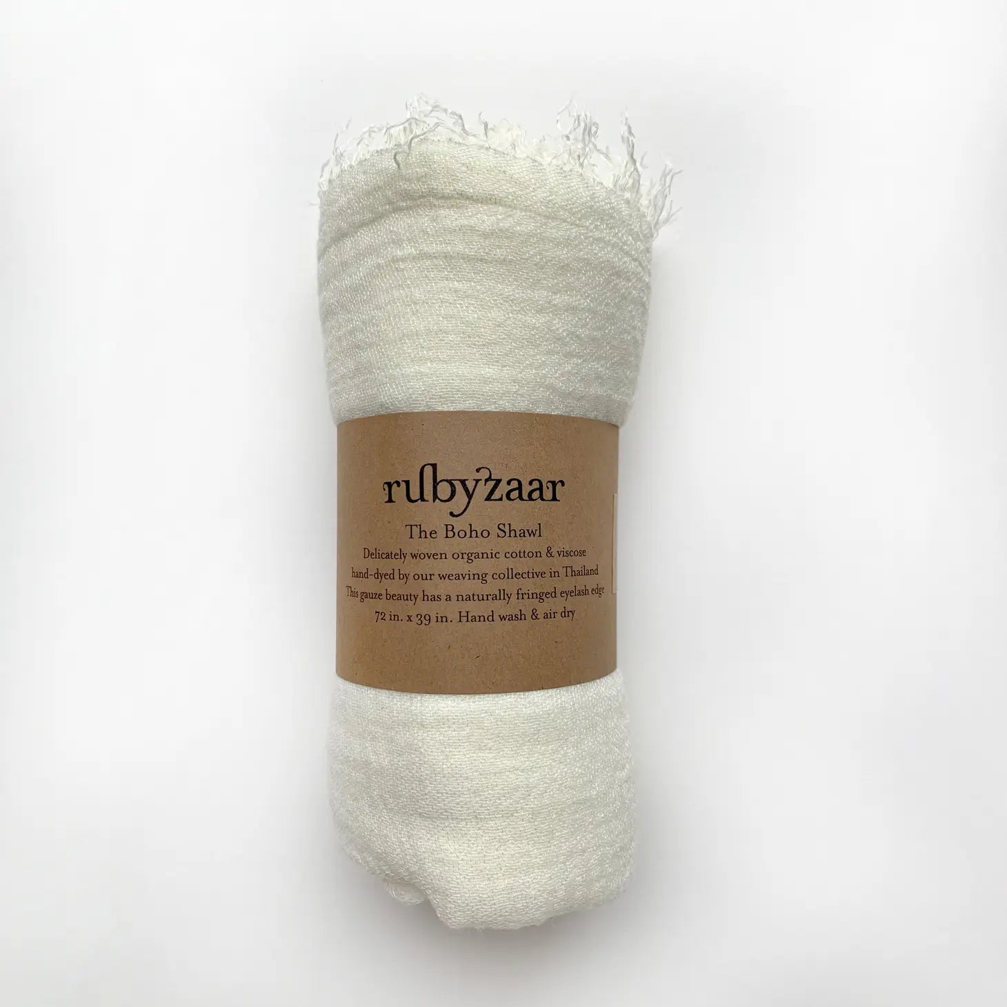 The Boho Scarf is a white shawl rolled up and wrapped with a brown paper band, featuring the "rubyzaar" label that highlights its handmade craftsmanship from organic cotton and viscose. This bohemian-style scarf, measuring 72 by 39 inches, recommends hand washing and air drying. It incorporates design details inspired by Thailand.