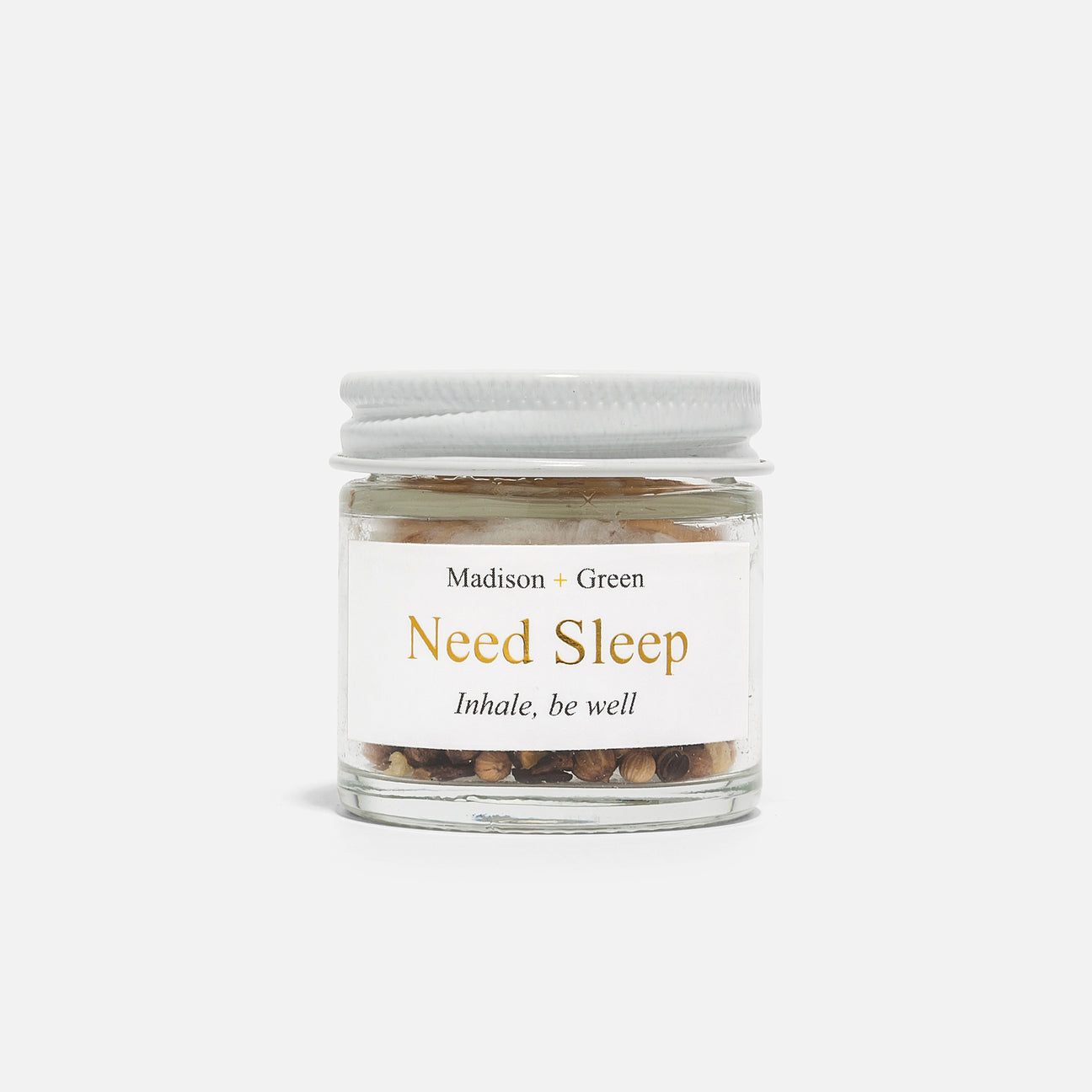 A small glass jar labeled "Madison + Green" showcases the product "Need Sleep" from a range of 13 varieties of Aromatherapy Inhalers. The tagline reads "Inhale, be well." This aromatherapy inhaler is designed with a white screw-on lid and filled with light brown and beige botanical ingredients, all infused with calming, stress-relieving scents. The background is plain white.