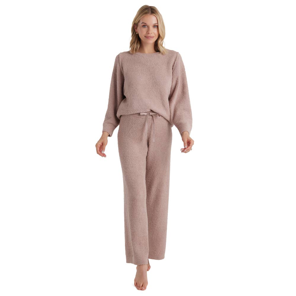 A person wearing the Marshmallow Lounge Set, Oprah's favorite cozy and textured women's outfit in a soft beige color, is barefoot against a plain white background. The set includes a long-sleeve top and matching pants with a drawstring waist, offering unmatched softness. They smile softly while wearing it.