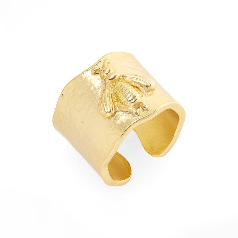 The Bumblebee Ring: Gold features 24 kt gold with a textured surface and embossed bee design. Its wide, open-back structure against a white backdrop, intricate detailing, and polished finish make it a standout in the elegant Bee collection.
