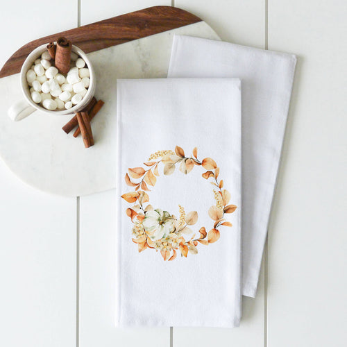 Two Tea Towels - Fall/Thanksgiving with a floral and pumpkin design are neatly arranged on a marble board from our Kitchen Collection. A nearby white cup holds marshmallows and cinnamon sticks, placed on a small wooden tray, all set against a white tiled background, showcasing handcrafted elegance.