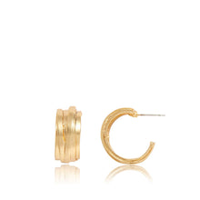 Load image into Gallery viewer, The Small Overlap Hoop Earrings are presented against a white background. One earring stands upright, showcasing its round shape and crossover design, while the other rests on its side, revealing the thin metal post. Both half hoop earrings have a polished finish that subtly reflects light.
