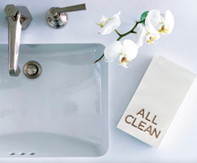 Load image into Gallery viewer, A white sink with a silver faucet features a white orchid branch on the right. Nearby, a folded foil-embossed towel reads &quot;ALL CLEAN&quot; in beige, adding elegance. The scene on the sleek countertop exudes sophistication reminiscent of the Cloth-Like Guest Towels - Year Round Themes.
