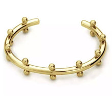 Load image into Gallery viewer, The Cindy Studded Cuff is an 18k gold-plated open cuff bracelet featuring evenly spaced small round studs along its edges. With a sleek, polished finish and a subtly curved design, this hypoallergenic and adjustable piece looks stunning against a plain white background.
