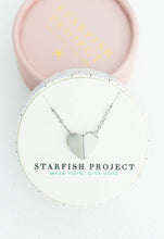 Load image into Gallery viewer, Displayed on a round white box, the Alexis Silver Heart Necklace shimmers in silver glory. The box features the text &quot;Starfish Project: Wear Hope, Give Hope.&quot; In the background, a pink lid partially reveals the words &quot;Starfish Project&quot; embossed in gold, adding an elegant touch.
