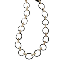 Load image into Gallery viewer, The image showcases The Perfect Chunky Mixed Metal Link Necklace, which features alternating large dark metal rings and smaller beige wood links. These elements create a striking contrast against a white background, emphasizing the bold design.
