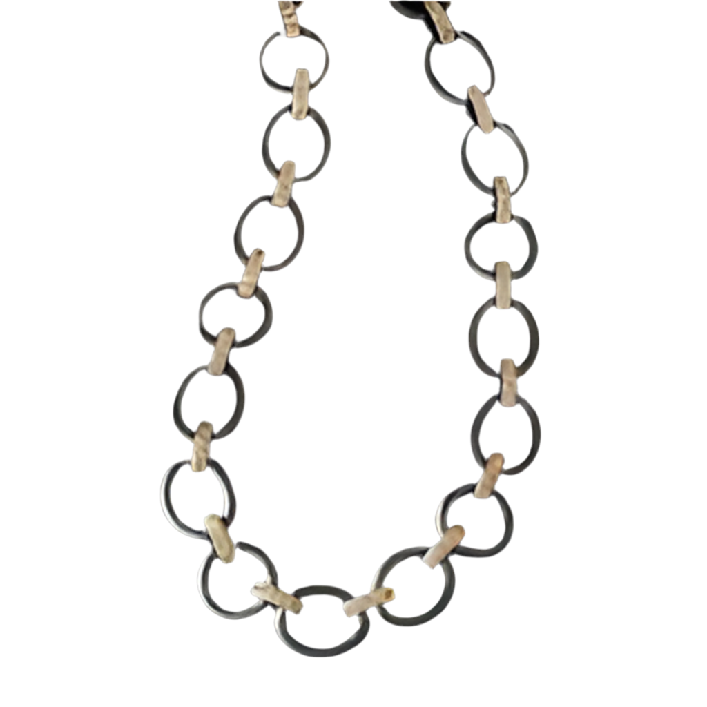 The image showcases The Perfect Chunky Mixed Metal Link Necklace, which features alternating large dark metal rings and smaller beige wood links. These elements create a striking contrast against a white background, emphasizing the bold design.