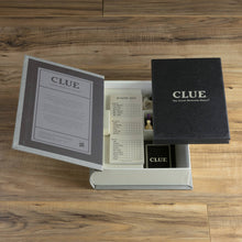 Load image into Gallery viewer, The Clue Vintage Bookshelf Edition box is displayed on a wooden surface, highlighting its vintage game board. The black board with &quot;CLUE&quot; on the cover, premium game components, game pieces, a deck of cards, and a detective notes pad are all neatly packed inside. Opening the lid reveals the classic instructions tucked inside.
