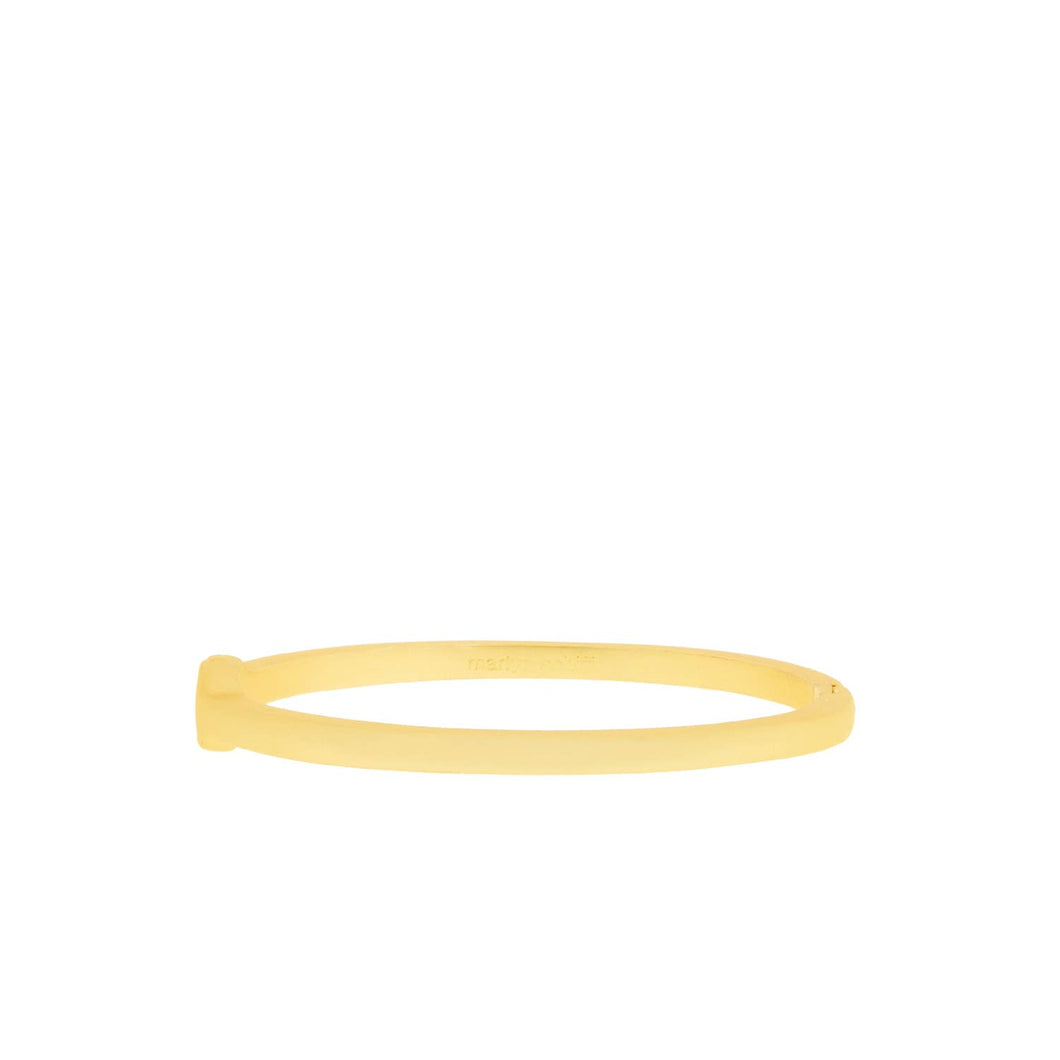 The Flat Hinge Bangle is a thin, gold-colored bracelet with a smooth, polished surface that measures 5 mm in width. Its simple yet elegant design is slightly oval-shaped and features a subtle hinge closure. The plain white background highlights the bracelet's sheen and minimalist style.