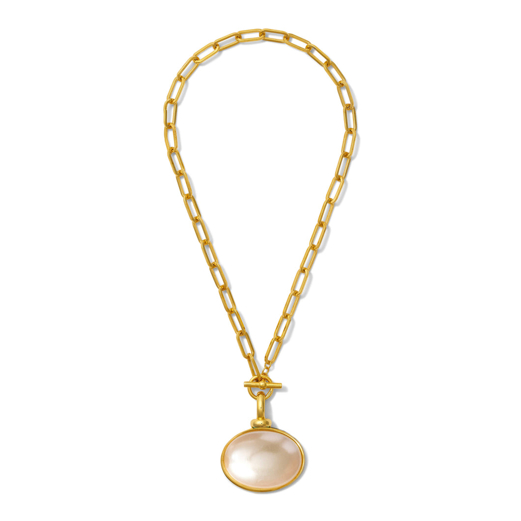 The Diana V. Pendant Necklace features elongated gold chain links and a large, smooth, mother of pearl-like round pendant set in a gold bezel. It closes with a toggle clasp, creating an elegant and modern look against a white background.