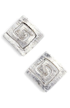 Load image into Gallery viewer, Close-up of a pair of Modern Square Spiral Stud Earrings with a textured silver surface. Each earring showcases a spiral design within the square, offering a layered, rustic appearance accentuated by an antique gold finish. Positioned at an angle, they enhance the three-dimensional effect of the spiral motif.
