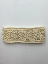 Load image into Gallery viewer, Introducing the Wool Knit Headband, a cream-colored accessory handmade in Nepal. This headband showcases an intricate floral pattern with delicately spaced flowers arranged in a row across the band. Fashioned from textured sheep wool, it beautifully highlights the detailed stitching of the floral design against its smooth white background.
