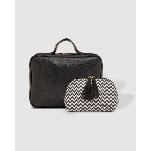 The Emma/Baby Audrey Cosmetic Bags - Set of 2, featuring a sophisticated black leather handbag with handle and gold zipper, and a stylish travel cosmetic case adorned with a black and white zigzag pattern and chic tassel, are gracefully displayed against a plain gray background.