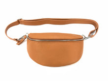 Load image into Gallery viewer, The Leather Bum Bag, crafted from light brown genuine leather with a textured finish, is positioned against a white background. It showcases a silver zipper and an adjustable strap complete with a silver clasp. The bag has dimensions of 10 x 6 x 2 inches and features a rounded shape, with the strap neatly arranged above it.
