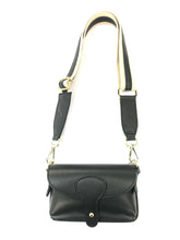 Load image into Gallery viewer, The Mini Crossbody - Leather is a genuine leather handbag with a black pebbled finish, featuring a flap closure and snap button. It comes with a wide, adjustable crossbody strap in black and cream adorned with gold-tone hardware. Its sleek and elegant design makes it ideal for both casual outings and as a fashionable stadium bag.
