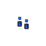 Load image into Gallery viewer, The Gold Plated Sapphire Princess and Emerald Cut Drop Post Earrings showcase a pair of gold-plated earrings with two stacked gemstones in striking blue hues. The top stone features a smaller, square princess cut, while the bottom stone is larger and rectangular in shape. These earrings have a simple yet elegant design set against a white background.
